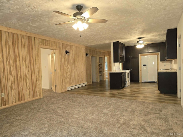 unfurnished living room with a baseboard radiator, wooden walls, dark colored carpet, and a textured ceiling