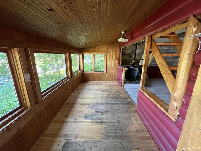 unfurnished sunroom with a wood stove, vaulted ceiling, and wooden ceiling