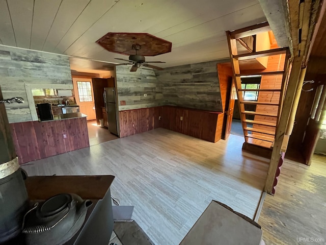 interior space featuring wooden walls, light hardwood / wood-style floors, a wealth of natural light, and ceiling fan