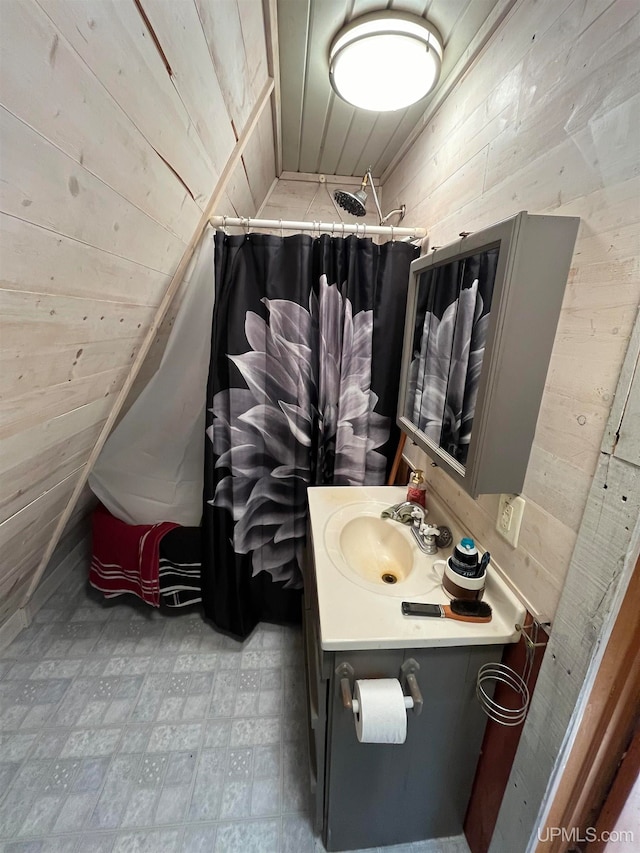 bathroom featuring vanity, wooden walls, and curtained shower