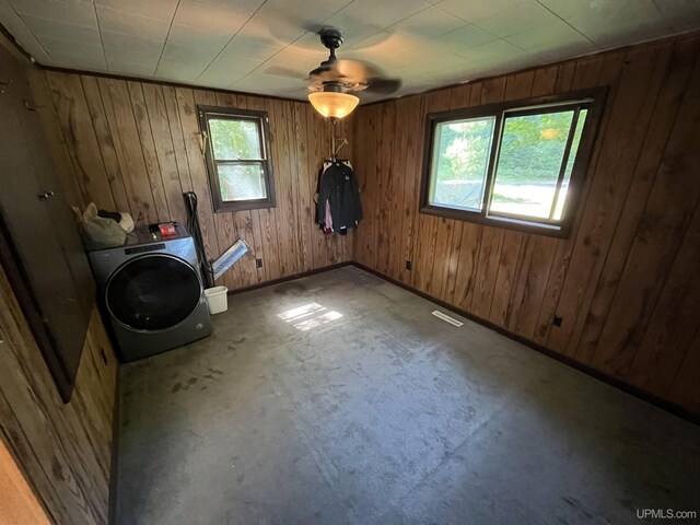 empty room with washer / clothes dryer, carpet floors, ceiling fan, a baseboard radiator, and wooden walls