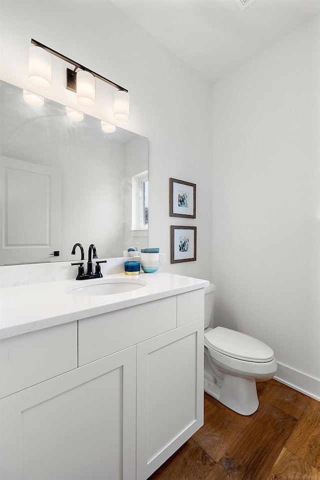 bathroom with hardwood / wood-style flooring, vanity, and toilet