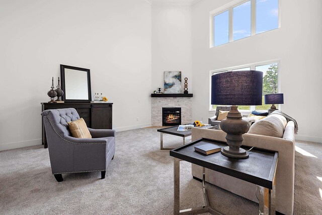 living room featuring light colored carpet, a fireplace, and a high ceiling