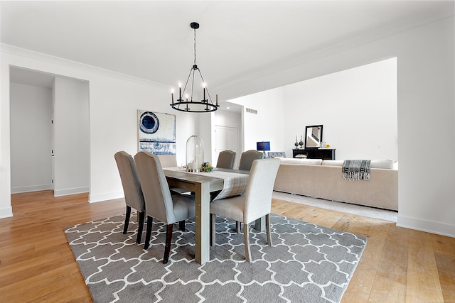 dining area with ornamental molding, an inviting chandelier, and wood-type flooring