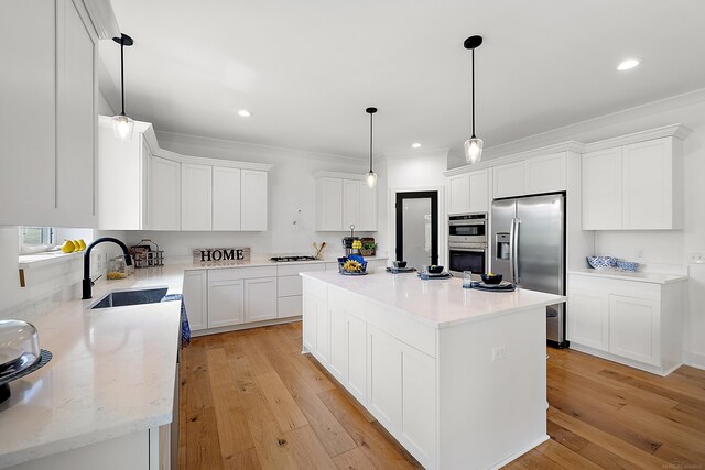 kitchen with a center island, decorative light fixtures, appliances with stainless steel finishes, light hardwood / wood-style floors, and white cabinets