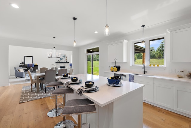 kitchen with sink, an inviting chandelier, light hardwood / wood-style floors, white cabinetry, and pendant lighting