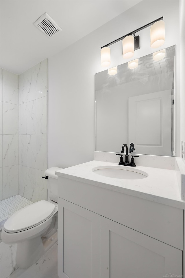 bathroom with toilet, vanity, and tiled shower