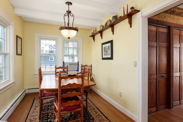 dining space featuring a healthy amount of sunlight, a baseboard radiator, beam ceiling, and wood finished floors