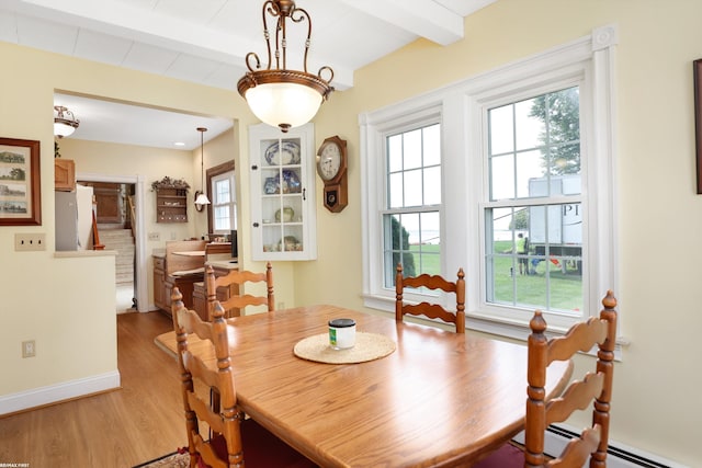 dining room with light wood finished floors, baseboards, a baseboard heating unit, and beamed ceiling