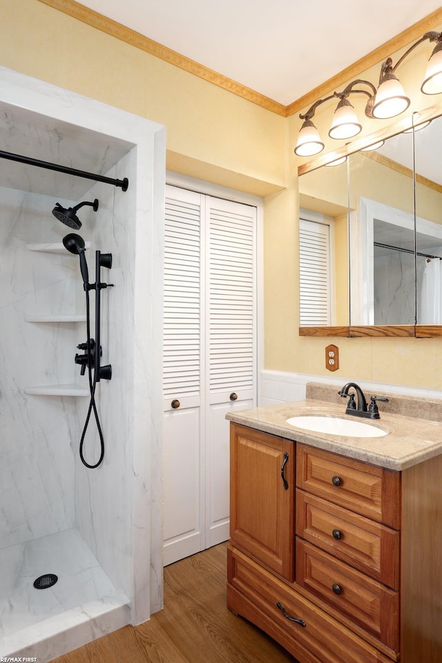 bathroom with a marble finish shower, ornamental molding, wood finished floors, vanity, and a closet