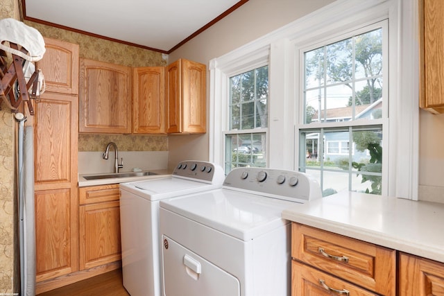 laundry room featuring cabinet space, ornamental molding, wood finished floors, separate washer and dryer, and a sink