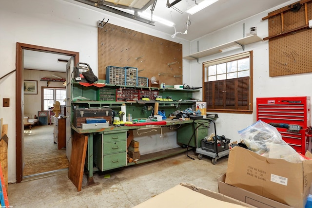 miscellaneous room with unfinished concrete flooring and a workshop area