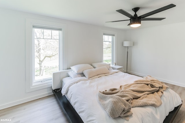 bedroom with ceiling fan, multiple windows, and hardwood / wood-style flooring