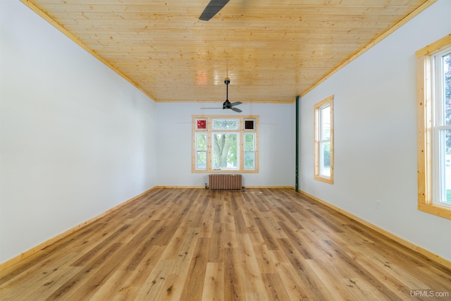 empty room with ceiling fan, a wealth of natural light, radiator, and light hardwood / wood-style flooring