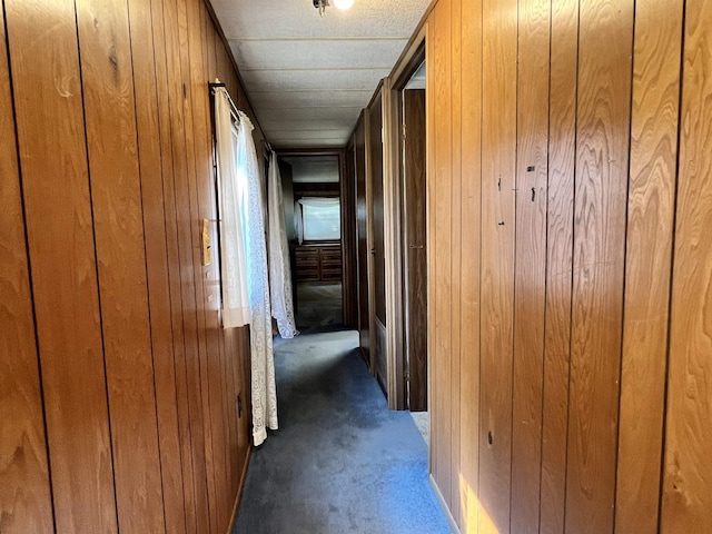 hallway with dark colored carpet and wooden walls