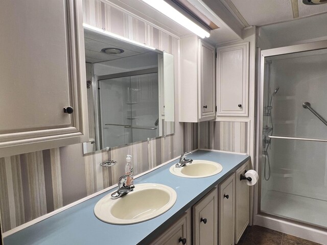 full bathroom with double vanity, a stall shower, and a sink