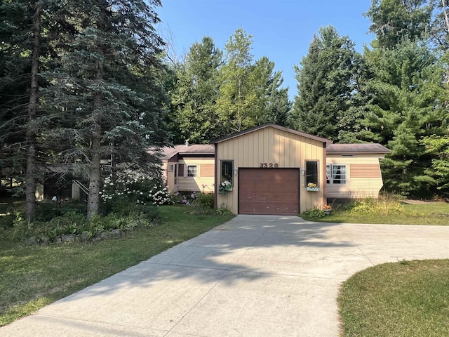 view of front of house featuring a garage, concrete driveway, a front lawn, and an outdoor structure