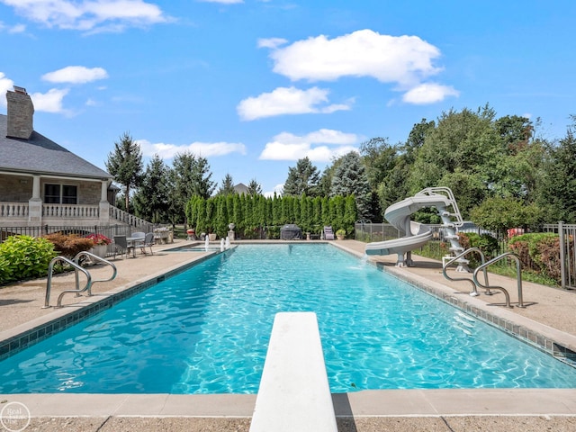 view of swimming pool featuring a diving board and a water slide