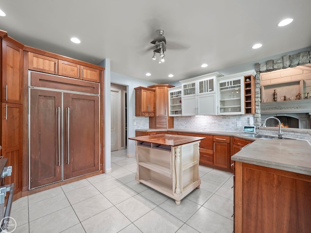 kitchen with backsplash, sink, paneled built in fridge, a center island, and ceiling fan