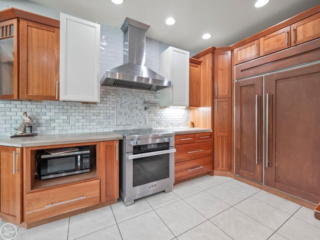 kitchen with light tile patterned floors, appliances with stainless steel finishes, decorative backsplash, and wall chimney range hood