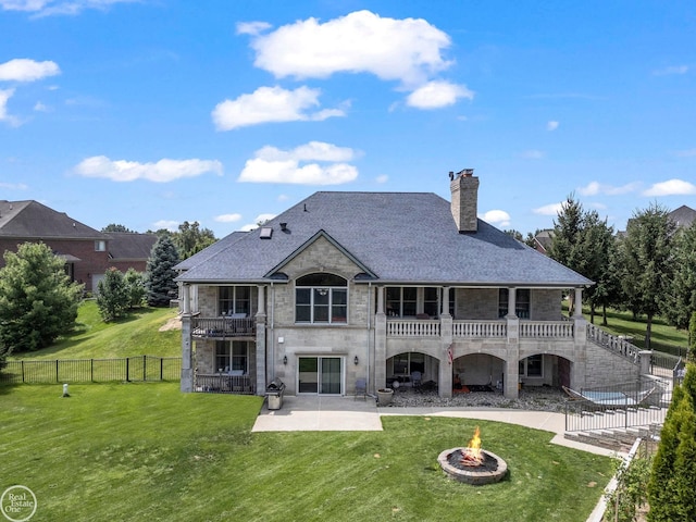 back of property with a lawn, an outdoor fire pit, a patio area, and a balcony