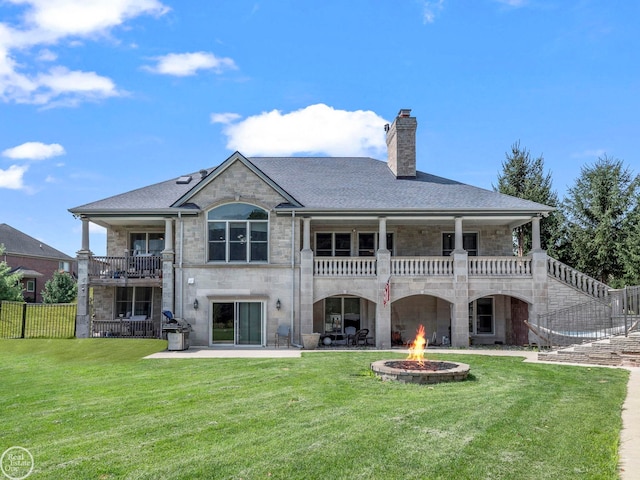 back of property featuring a balcony, an outdoor fire pit, a patio area, and a yard