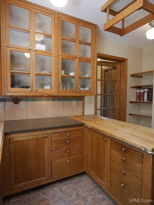 kitchen with dark stone countertops and dark tile patterned floors