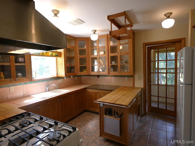 kitchen with wall chimney range hood, plenty of natural light, range, and white fridge