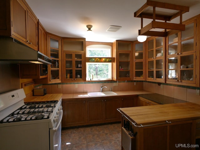 kitchen with sink, dark tile patterned floors, white range oven, and tasteful backsplash