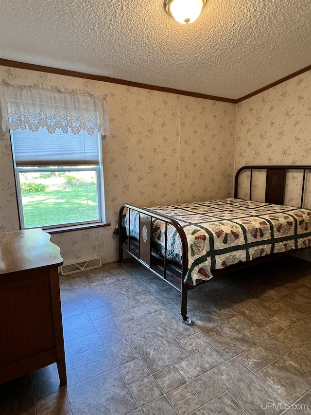bedroom with wallpapered walls, visible vents, and a textured ceiling