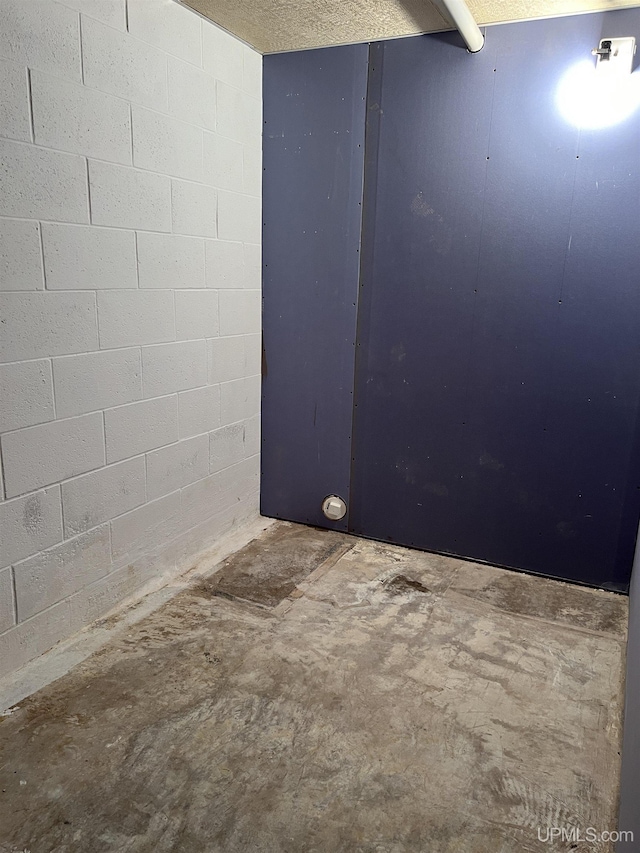 spare room featuring concrete flooring and concrete block wall