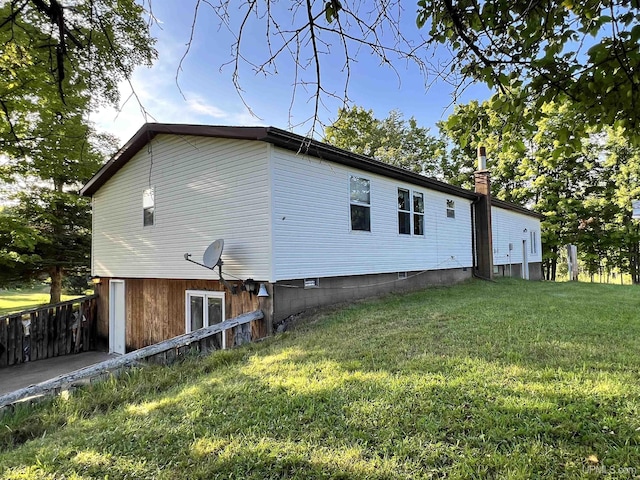 view of side of property featuring crawl space, a yard, and a chimney