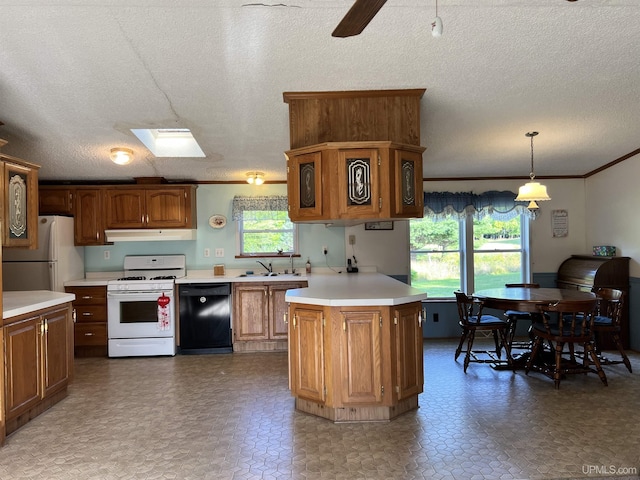 kitchen with white appliances, under cabinet range hood, light countertops, and a wealth of natural light