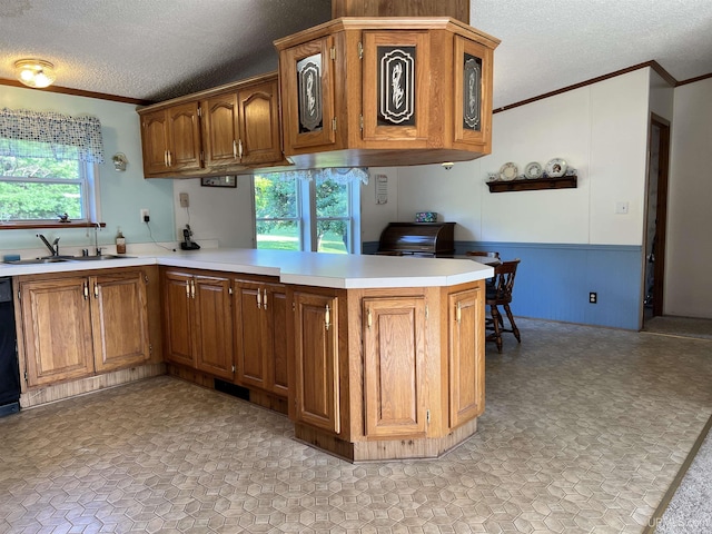 kitchen featuring crown molding, a peninsula, a sink, and brown cabinets