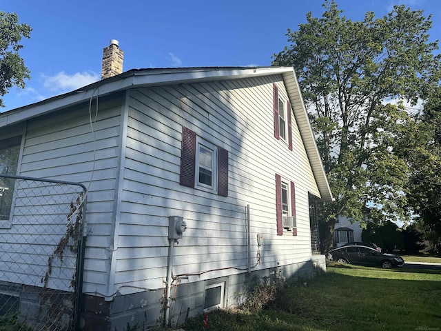 view of side of property featuring a lawn and a chimney