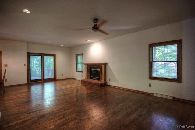 unfurnished living room with a healthy amount of sunlight, wood-type flooring, and a brick fireplace