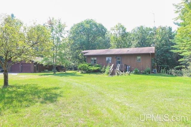 view of yard featuring central AC unit and a garage