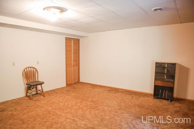 carpeted spare room featuring a drop ceiling