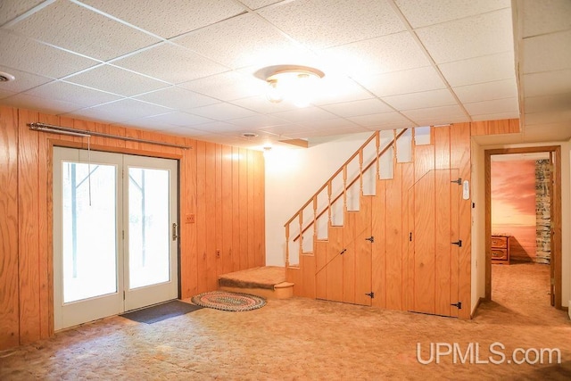 interior space with wood walls, carpet, and a paneled ceiling