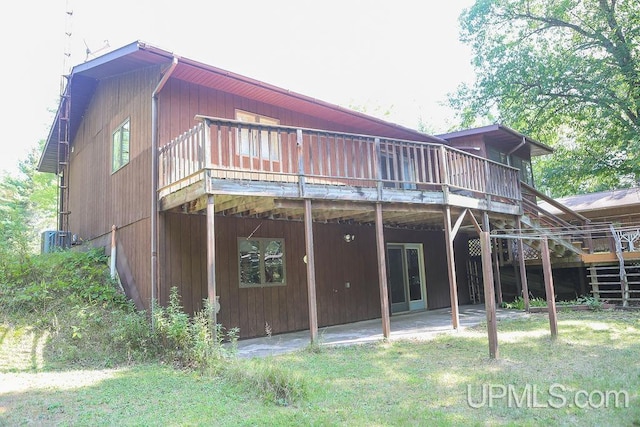 rear view of house featuring a lawn, a wooden deck, and central AC