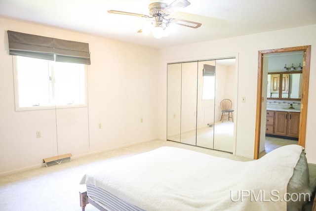 bedroom featuring carpet, sink, a closet, ensuite bathroom, and ceiling fan