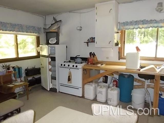 kitchen featuring white appliances, white cabinetry, and concrete flooring