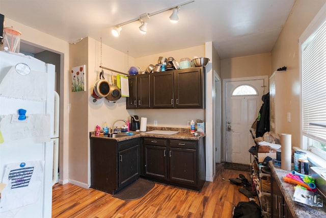 kitchen featuring light hardwood / wood-style floors, dark brown cabinets, light stone counters, and white fridge