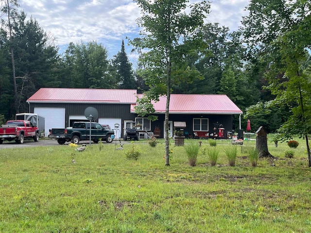 rear view of property with a garage, a lawn, and an outbuilding