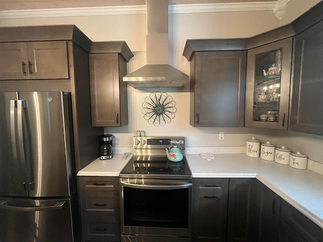 kitchen with ornamental molding, dark brown cabinets, wall chimney range hood, and stainless steel appliances