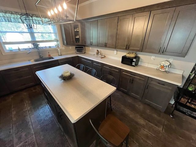 kitchen featuring pendant lighting, dark brown cabinets, a chandelier, dark hardwood / wood-style floors, and a kitchen island