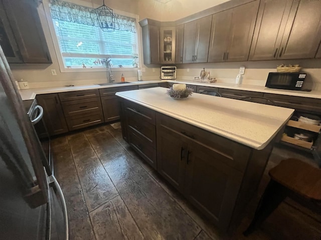 kitchen featuring dark brown cabinetry, sink, dark wood-type flooring, and decorative light fixtures