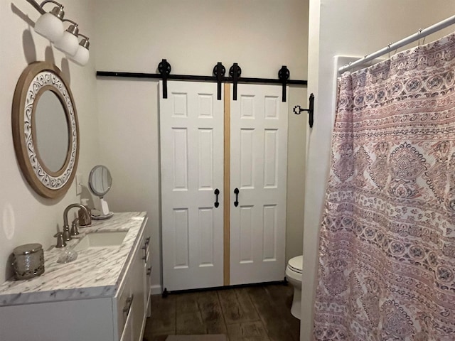 bathroom featuring wood-type flooring, a shower with curtain, vanity, and toilet