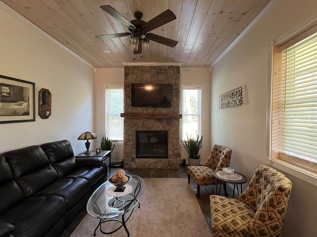 carpeted living room with ceiling fan, a stone fireplace, wooden ceiling, and a wealth of natural light