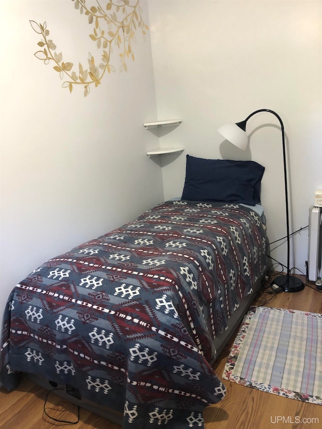 bedroom with radiator heating unit and hardwood / wood-style flooring